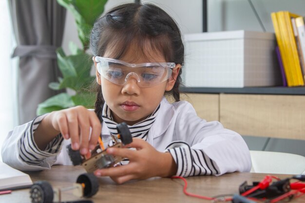 Étudiante fabriquant des voitures robotiques Une fille à l'école de robotique rend le robot géré par le constructeur l'enfant apprend la construction de robots