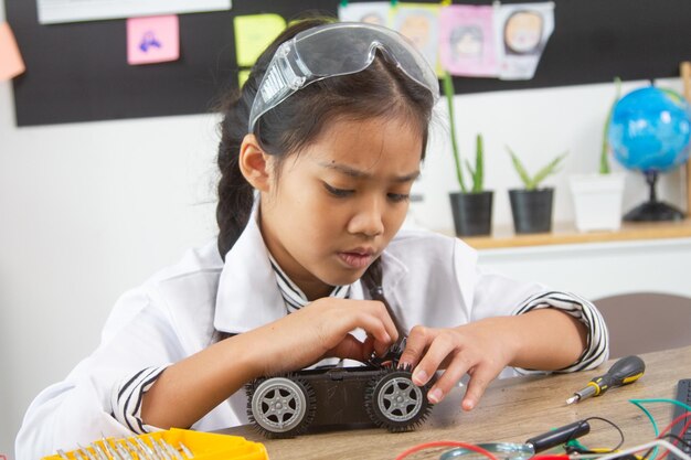 Étudiante fabriquant des voitures robotiques Une fille à l'école de robotique rend le robot géré par le constructeur l'enfant apprend la construction de robots