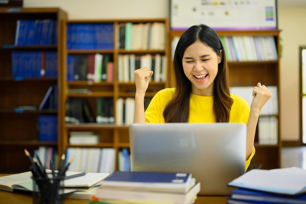 Une étudiante heureuse et excitée regardant un ordinateur portable lisant de bonnes nouvelles a réussi l'examen a reçu une notification d'admission à l'université