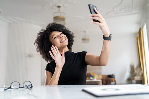 Une étudiante indépendante en communication vidéo qui étudie en ligne utilise le téléphone au bureau