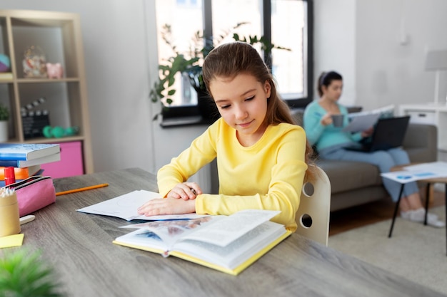 étudiante avec un livre écrit dans un bloc-notes à la maison