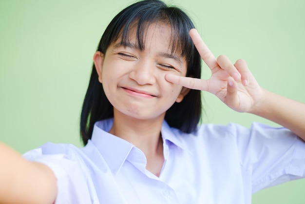 Une étudiante mignonne fait un slefie par téléphone intelligent, porte un uniforme scolaire, une fille asiatique.
