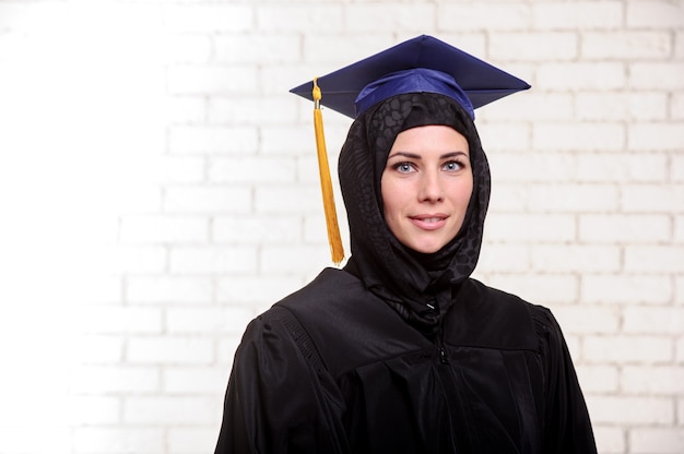 Une étudiante musulmane diplômée heureuse pose avec un diplôme à l'intérieur