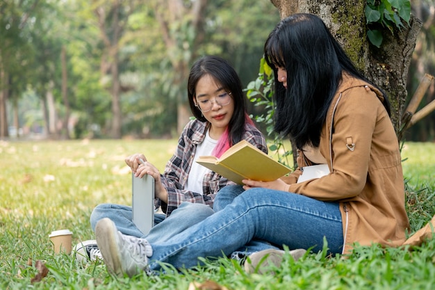 Une étudiante parle et étudie avec son amie dans le parc du campus.