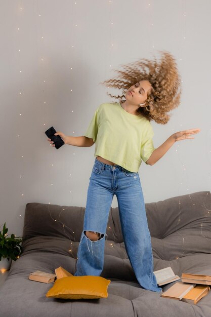 Une étudiante a pris une pause dans la préparation des examens et danse et s'amuse parmi les livres