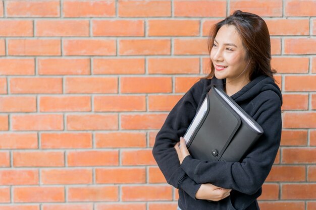 Une étudiante se tient au mur du campus