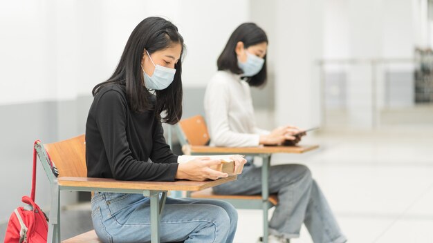 Des étudiantes adolescentes portant un masque facial et gardent leurs distances tout en étudiant en classe et sur le campus universitaire pour prévenir la pandémie de COVID-19. Éducation stock photo