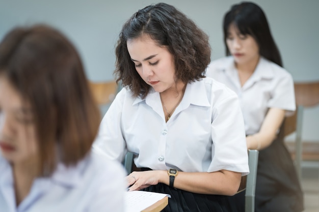 Les étudiants adolescents écrivent sur la feuille de réponses du papier d'examen dans la salle de classe