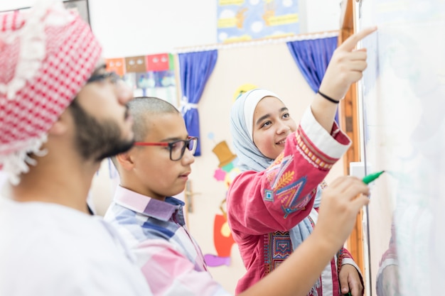 Photo des étudiants arabes musulmans résolvent une question mathématique sur le tableau blanc