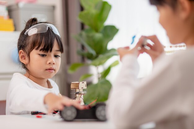 Les étudiants asiatiques apprennent à la maison à coder des voitures robotiques et des câbles électroniques en STEM STEAM mathématiques ingénierie science technologie code informatique en robotique pour enfants concept