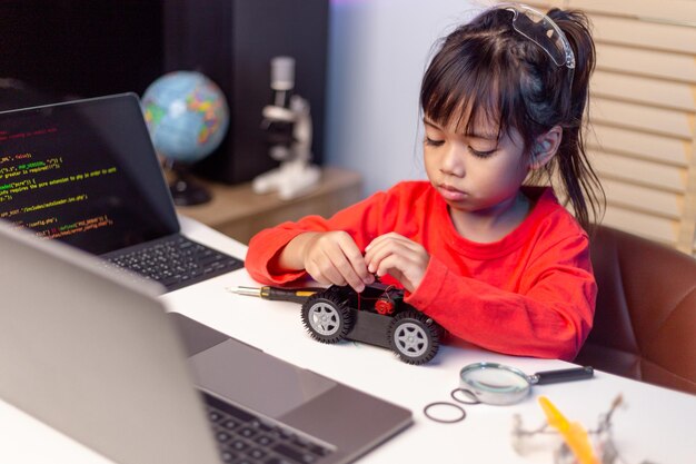 Les étudiants asiatiques apprennent à la maison à coder des voitures robotisées et des câbles de cartes électroniques dans STEM STEAM mathématiques ingénierie science technologie code informatique dans la robotique pour le concept des enfants