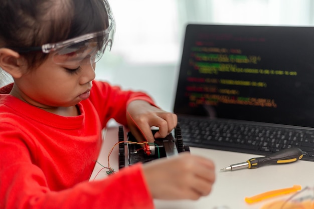 Les étudiants asiatiques apprennent à la maison à coder des voitures robotisées et des câbles de cartes électroniques dans STEM STEAM mathématiques ingénierie science technologie code informatique dans la robotique pour le concept des enfants