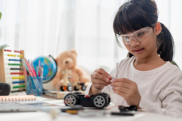 Les étudiants asiatiques apprennent à la maison à coder des voitures robotisées et des câbles de cartes électroniques dans STEM STEAM mathématiques ingénierie science technologie code informatique dans la robotique pour le concept des enfants