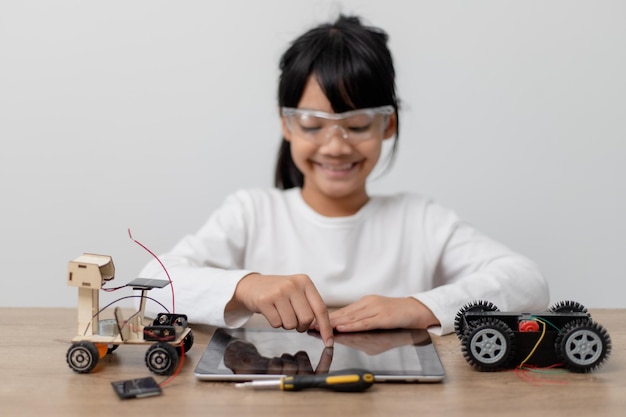 Les étudiants asiatiques apprennent à la maison à coder des voitures robotisées et des câbles de cartes électroniques dans STEM STEAM mathématiques ingénierie science technologie code informatique dans la robotique pour le concept des enfants