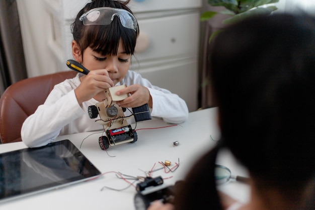 Les étudiants asiatiques apprennent à la maison à coder des voitures robotisées et des câbles de cartes électroniques dans STEM STEAM mathématiques ingénierie science technologie code informatique dans la robotique pour le concept des enfants