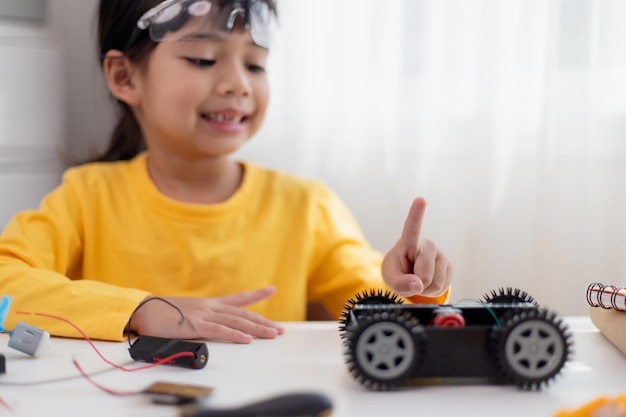 Les étudiants asiatiques apprennent à la maison à coder des voitures robotisées et des câbles de cartes électroniques dans STEM STEAM mathématiques ingénierie science technologie code informatique dans la robotique pour le concept des enfants