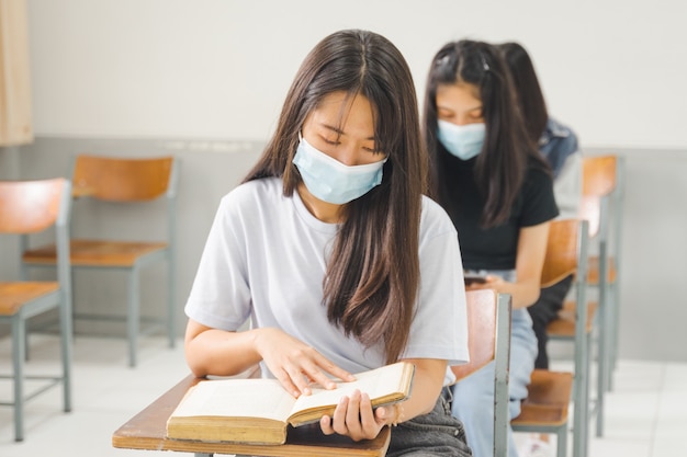 Les étudiants asiatiques de retour à l'école portent un masque facial et gardent la distance en étudiant en classe