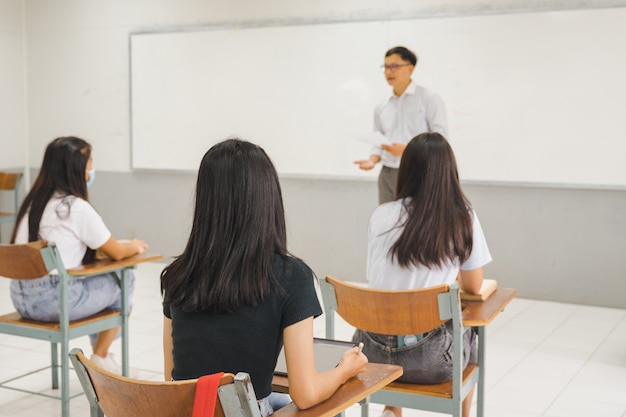 Les étudiants asiatiques de retour à l'école portent un masque facial et gardent la distance en étudiant en classe