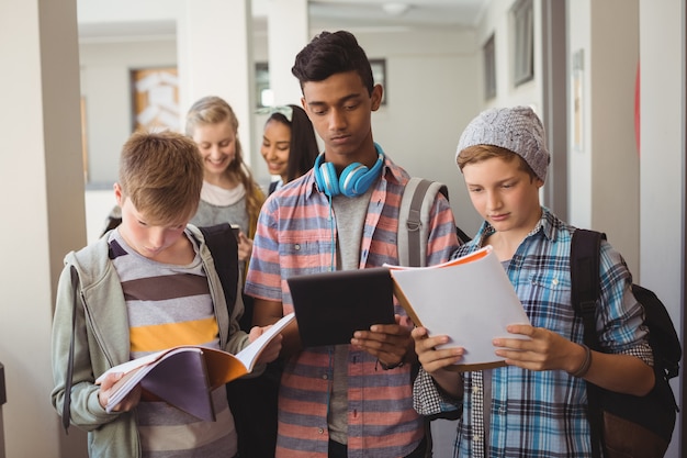 Étudiants debout avec ordinateur portable et tablette numérique dans le couloir