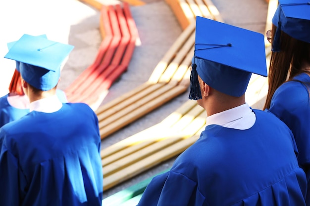 Étudiants diplômés portant un chapeau et une robe de graduation à l'extérieur