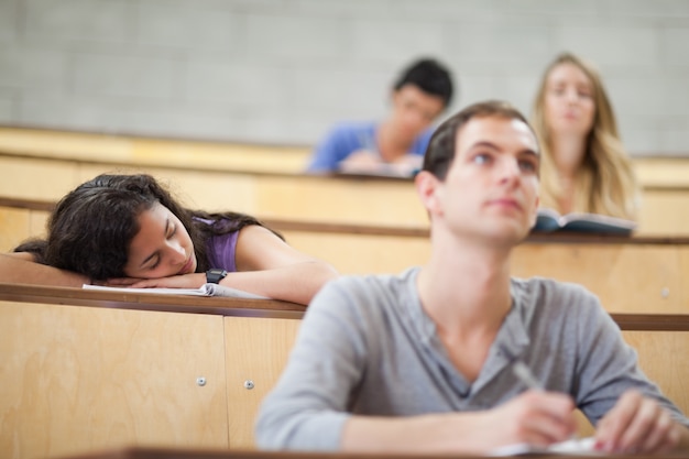 Les étudiants écoutent un conférencier pendant que leur camarade dort