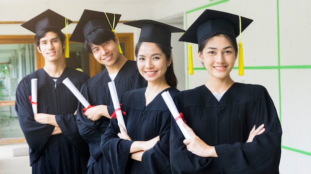 les étudiants étudiants homme et femme avec des robes de graduation noires détiennent le diplôme