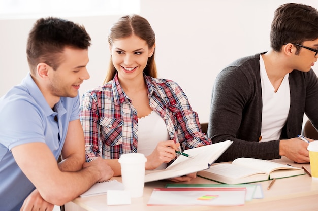 Les étudiants étudient. Trois étudiants confiants qui étudient assis au bureau ensemble