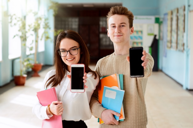 Des étudiants heureux montrent les écrans de leurs smartphones à la caméra