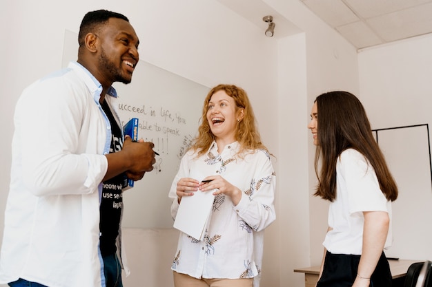 Des étudiants heureux multiethniques et un enseignant noir étudient les langues étrangères et sourient et rient ensemble en classe