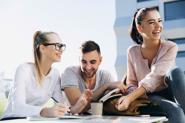 Des étudiants heureux travaillent et étudient à la table à l&#39;air frais