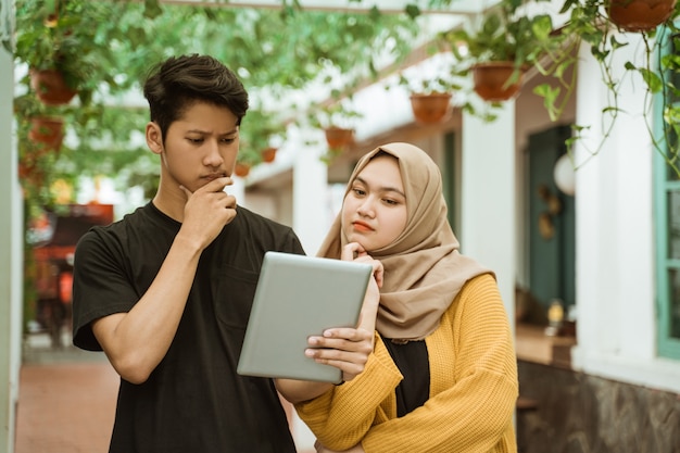 Les étudiants Masculins Et Hijab S'inquiètent En Regardant L'écran De La Tablette