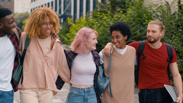 Des étudiants multiraciaux heureux et souriants, une diversité multiethnique, des amis marchant dans l'université de la ville.