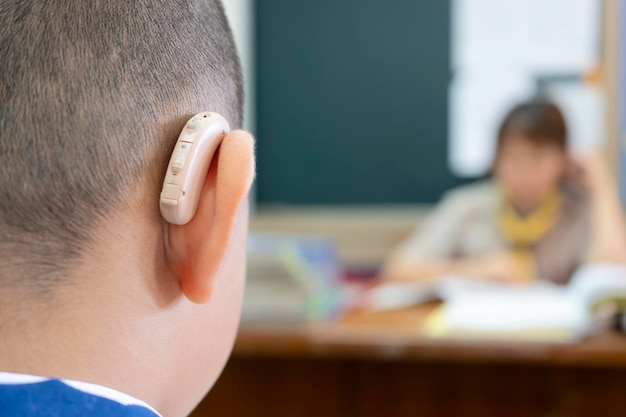 Les étudiants qui portent des appareils auditifs pour augmenter l'efficacité auditive Aide à pouvoir apprendre autant qu'un ami L'arrière-plan est un enseignant qui lui parle