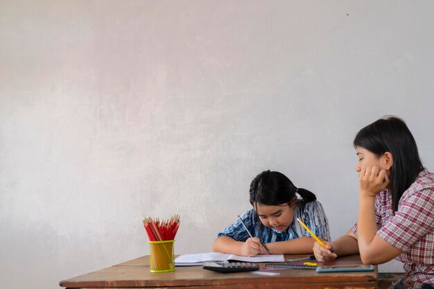 Les étudiants résolvent le concept de problèmes mathématiquesLe professeur enseigne à une fille asiatique Ils apprennent les mathématiques