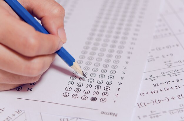 Photo Étudiants tenant un crayon écrivant un choix choisi sur des feuilles de réponses