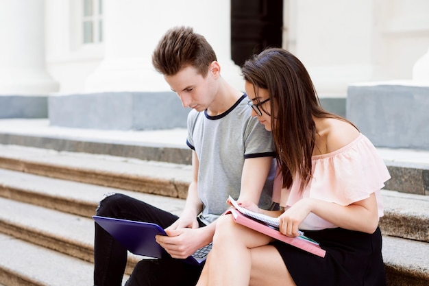 Étudiants Universitaires Assis Ensemble Dans Les Escaliers Avec Un Ordinateur Portable Moderne Violet Et Des Livres Faisant Des Recherches