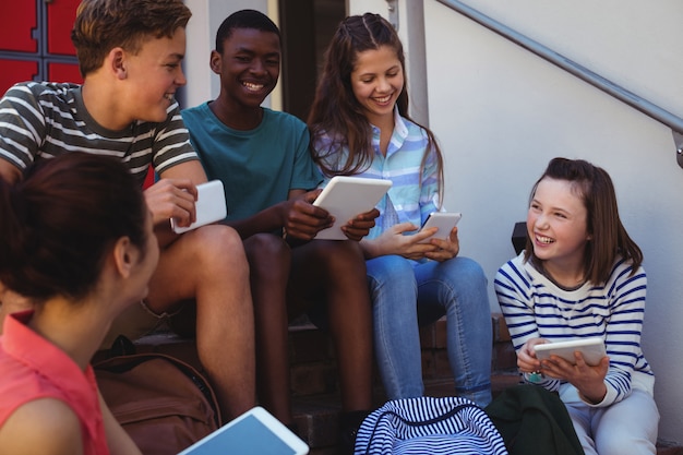 Photo les étudiants utilisant un téléphone mobile et une tablette numérique sur l'escalier