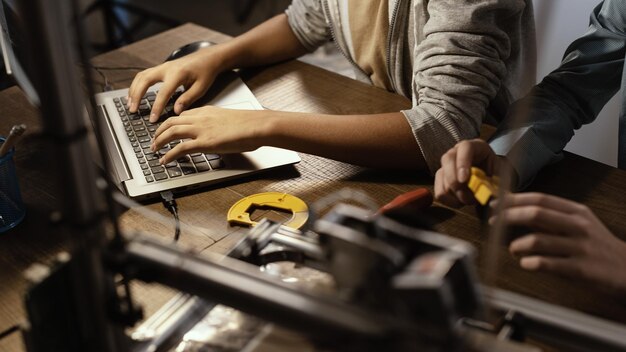 Photo les étudiants utilisent une imprimante 3d et un ordinateur portable pour imprimer des prototypes en plastique