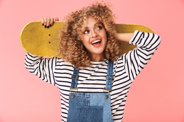 European curly girl 20s tenant la planche à roulettes en position debout