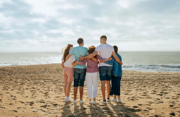 Les européens et arabes du millénaire dans des câlins décontractés profitent de la liberté d'équipe sur la plage à