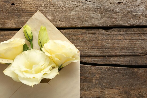 Eustoma blanc dans l'enveloppe sur le fond en bois