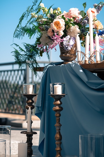 événement traiteur cadre fleurs bougies bleu serviettes et nappe tables en bois à l'extérieur