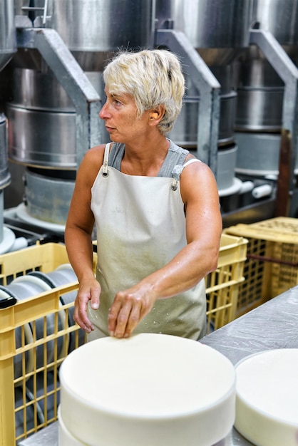 Evillers, France - 31 août 2016 : Fromager mettant le jeune fromage Gruyère de Comte dans les formes à la laiterie en Franche Comté, Bourgogne, France.