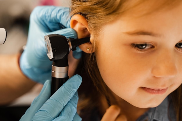 Examen en gros plan de l'oreille de l'enfant avec otoscope Otoscopie Visite chez le médecin ORL et consultation