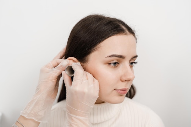 Examen en gros plan de l'oreille de la femme avec entonnoir auriculaire Otoscopie Visite chez le médecin ORL et consultation