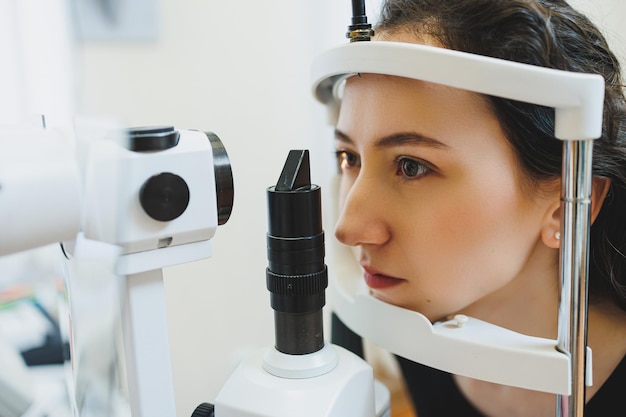Examen de la vision sur un équipement ophtalmologique moderne Examen de la vue d'une femme lors d'un rendez-vous chez un ophtalmologiste à l'aide de microscopes Traitement de la vision lors d'un rendez-vous chez un ophtalmologiste