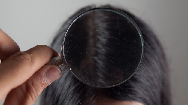 Examine les cheveux d'une jeune femme avec une loupe