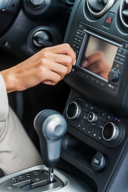 Examiner sa nouvelle voiture. Close-up of woman in formalwear touchant le tableau de bord avec le doigt alors qu'il était assis dans la voiture