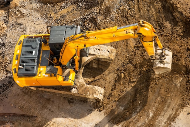 Excavatrice au sol d'un chantier de construction avec une vue aérienne de dessus de godet surélevé