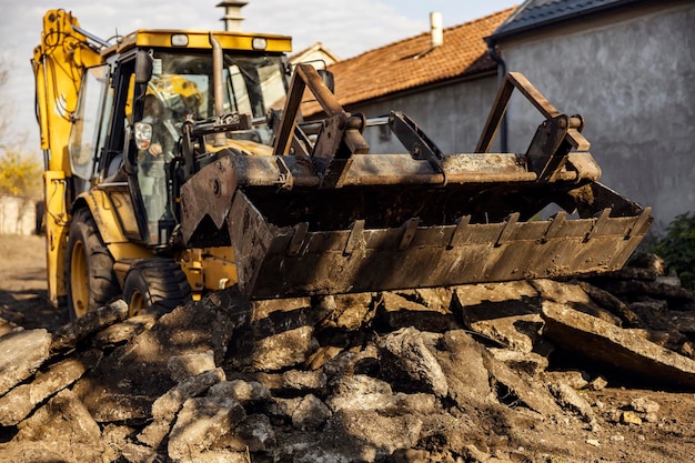 Une excavatrice cassant l'asphalte et enlevant des roches du chantier de construction